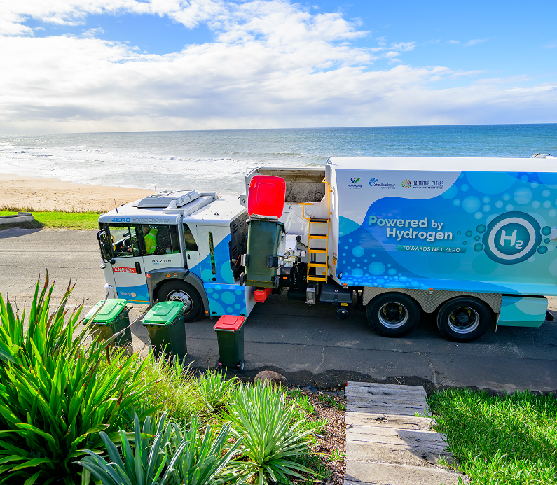 Garbage truck powered by hydrogen picking up bins near a beach