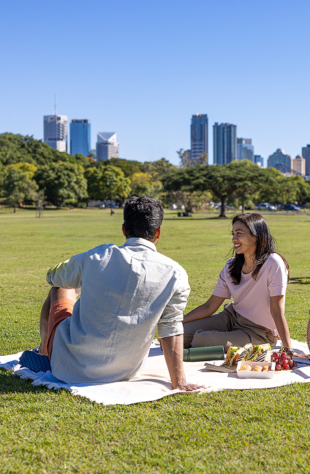Couple enjoying a picnic on the grass in a park with city skyline view