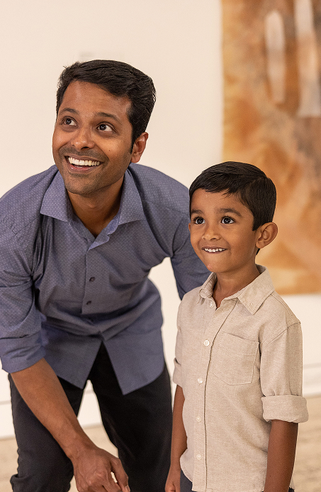 Father and son from a migrant background viewing art in a gallery