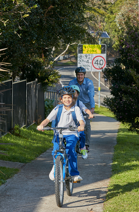 Parent and two children cycling together to school