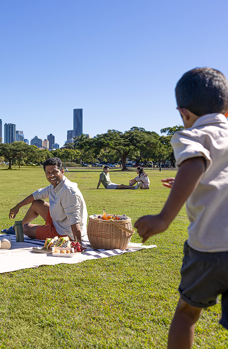 Son running toward his father during a family picnic in a park close to the CBD