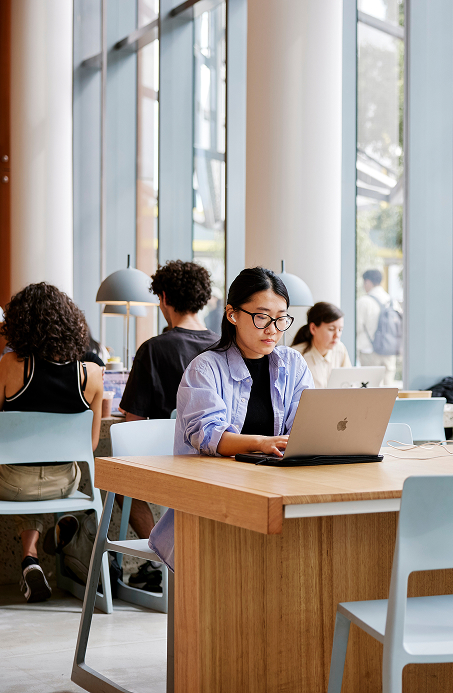 Student with laptop sitting in an open study area at university