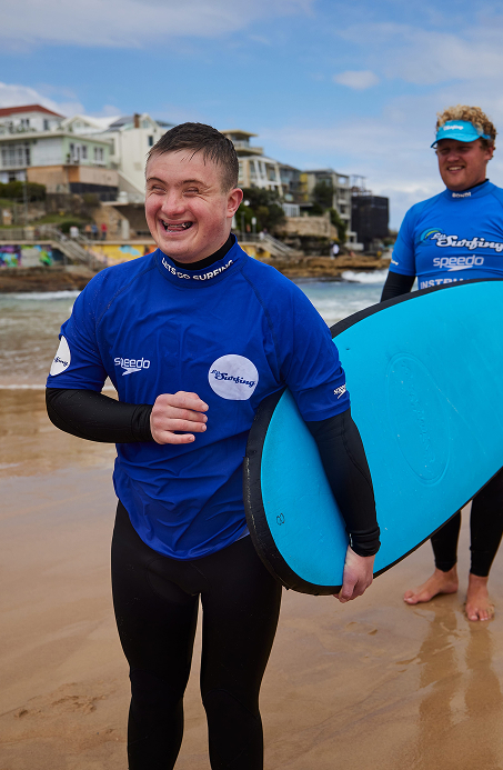Surf instructor teaching surfing to a boy with Down syndrome at Bondi Beach