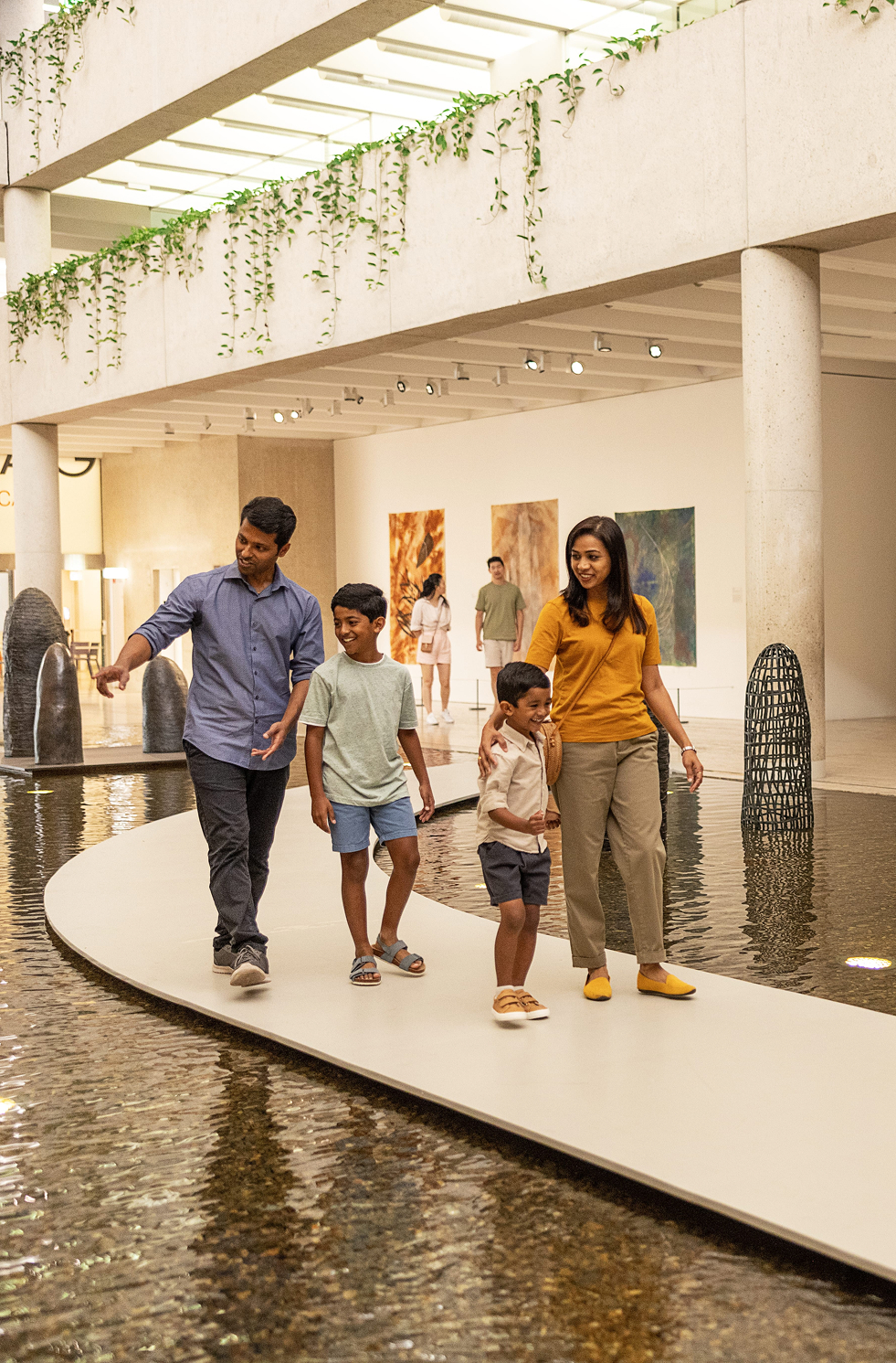 Family strolling through light-filled galleries at QAGOMA, admiring sculptures and paintings