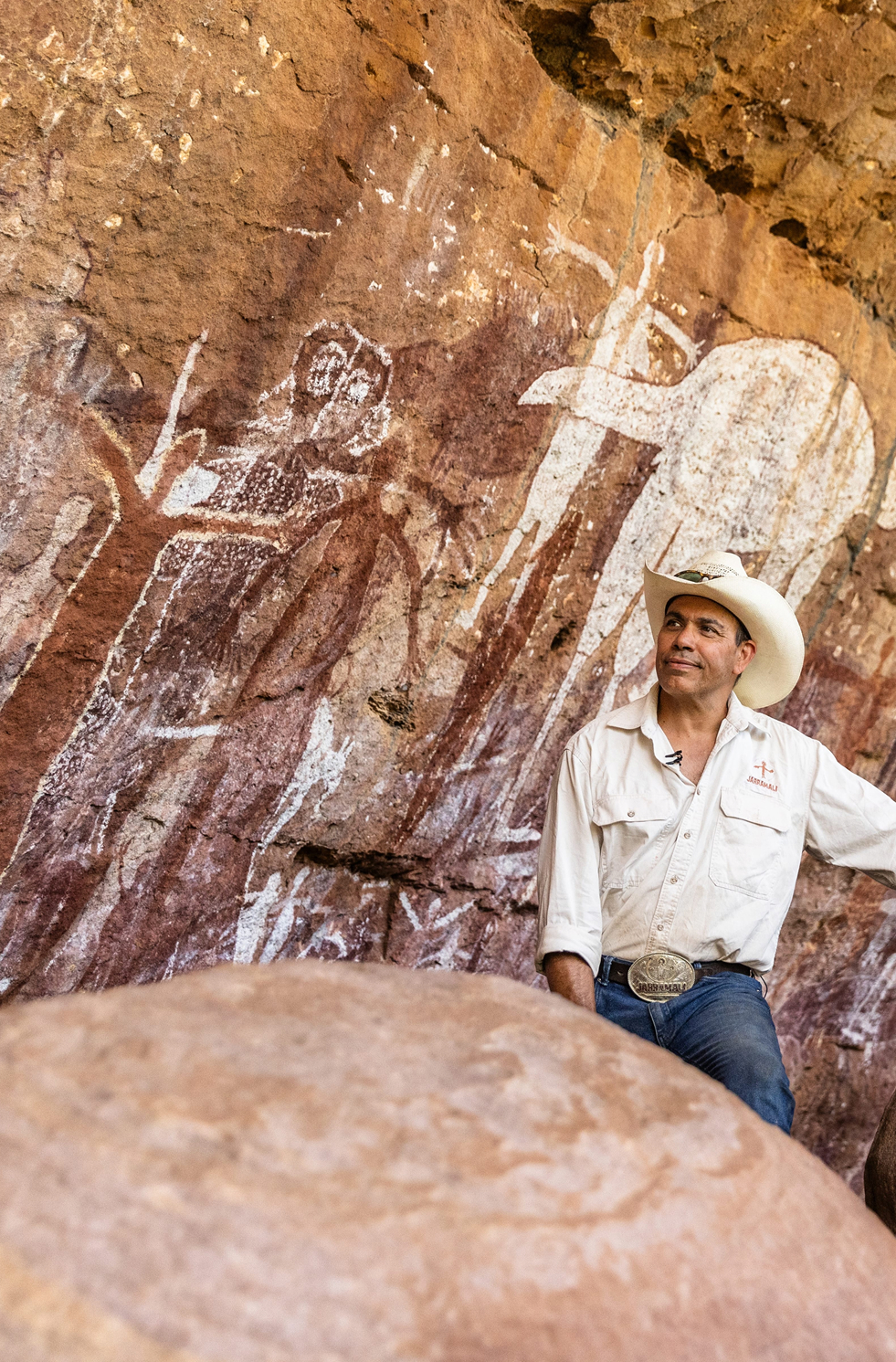 Indigenous man next to ancient cave art at Laura, Cook