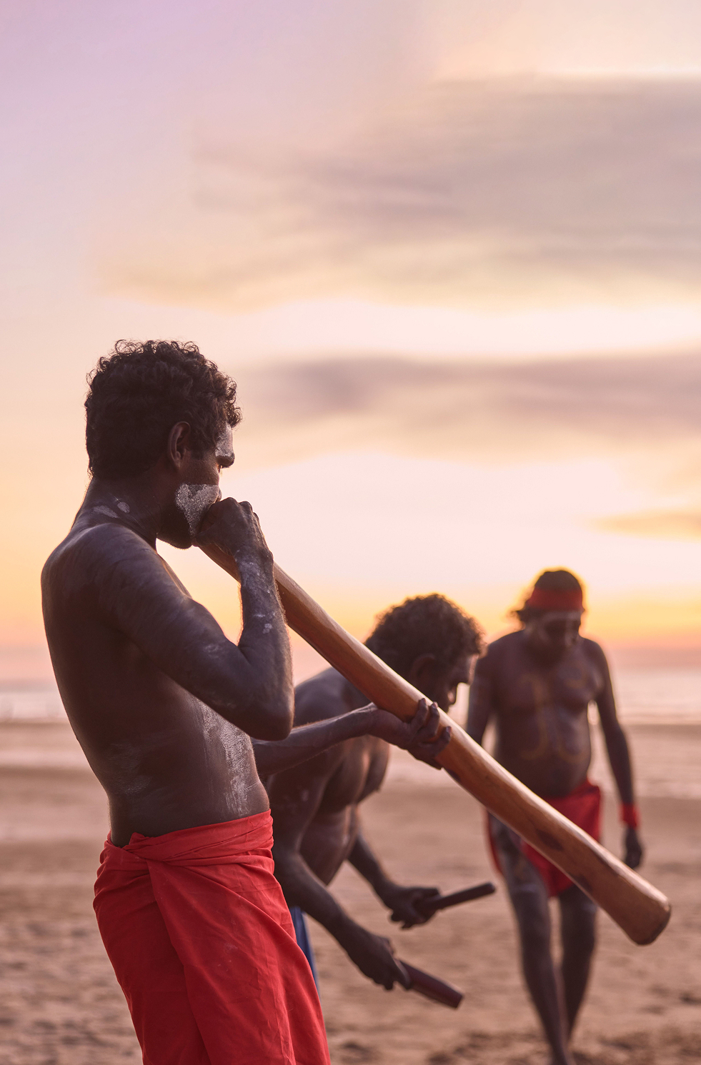 Indigenous performers with didgeridoo and clapsticks sharing dance and stories at sunset, Casuarina Coastal Reserve, Darwin