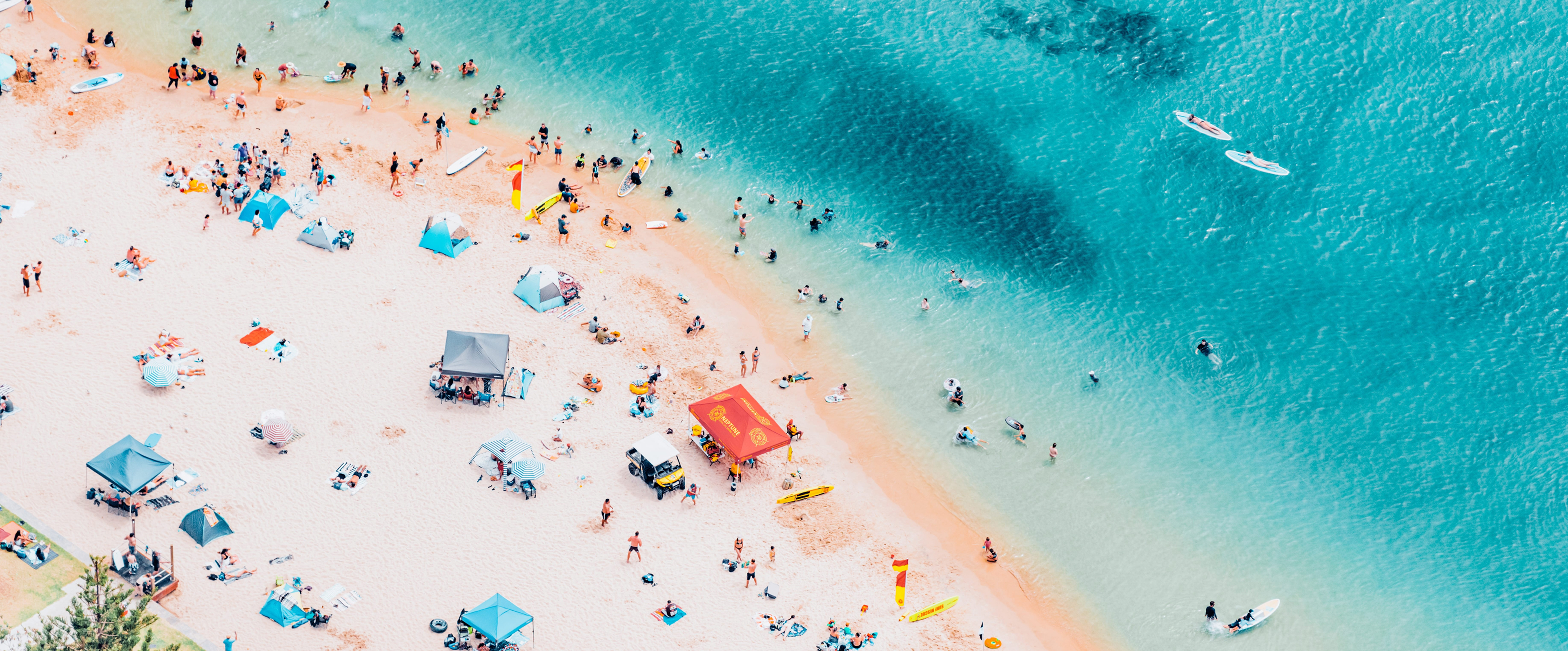 Aerial view of Tallebudgera Creek, Gold Coast, with beachgoers relaxing and swimming in blue water