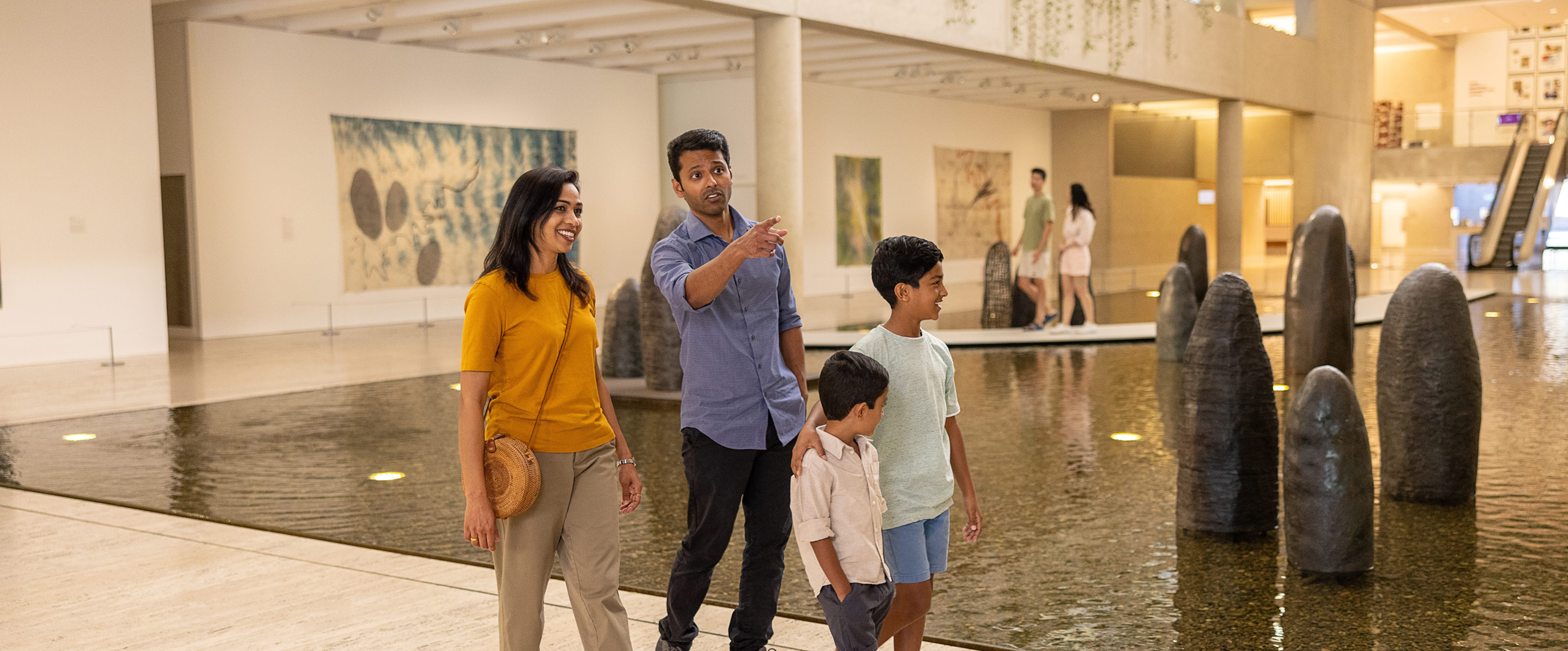 Family exploring spacious galleries at QAGOMA, pausing to view diverse artworks