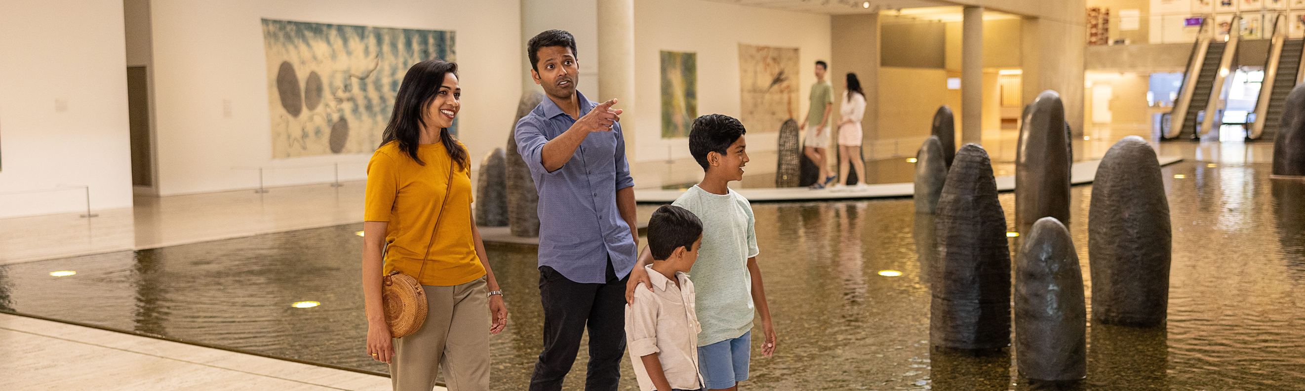 Family exploring spacious galleries at QAGOMA, pausing to view diverse artworks