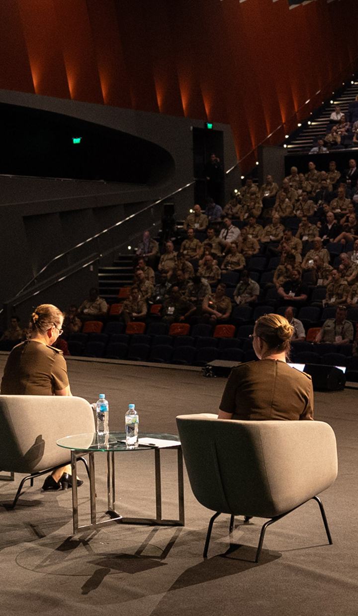 An auditorium filled with military personnel watching women on stage