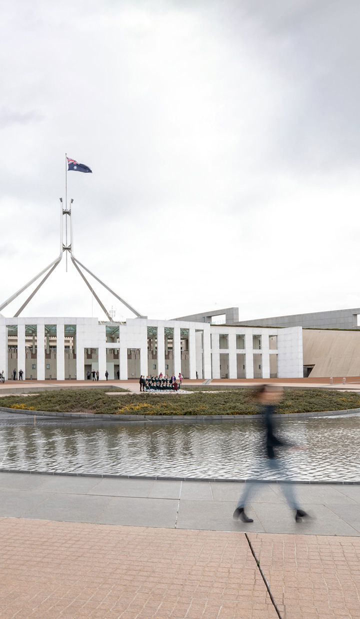 Blurred image of a person walking in front of Parliament House in Canberra