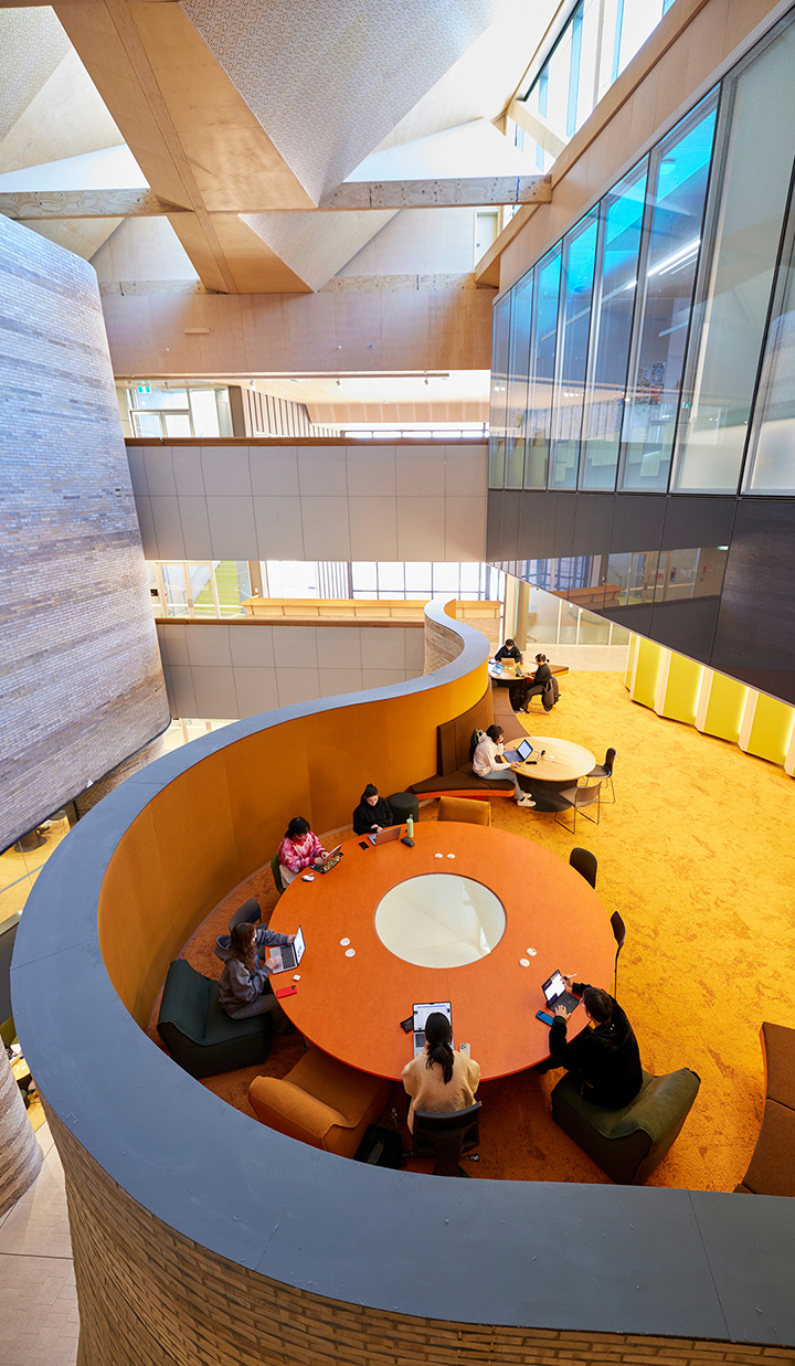Monash University campus interior with students studying on their laptops