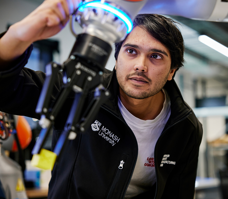 Engineer at Monash University making adjustments to a robot.