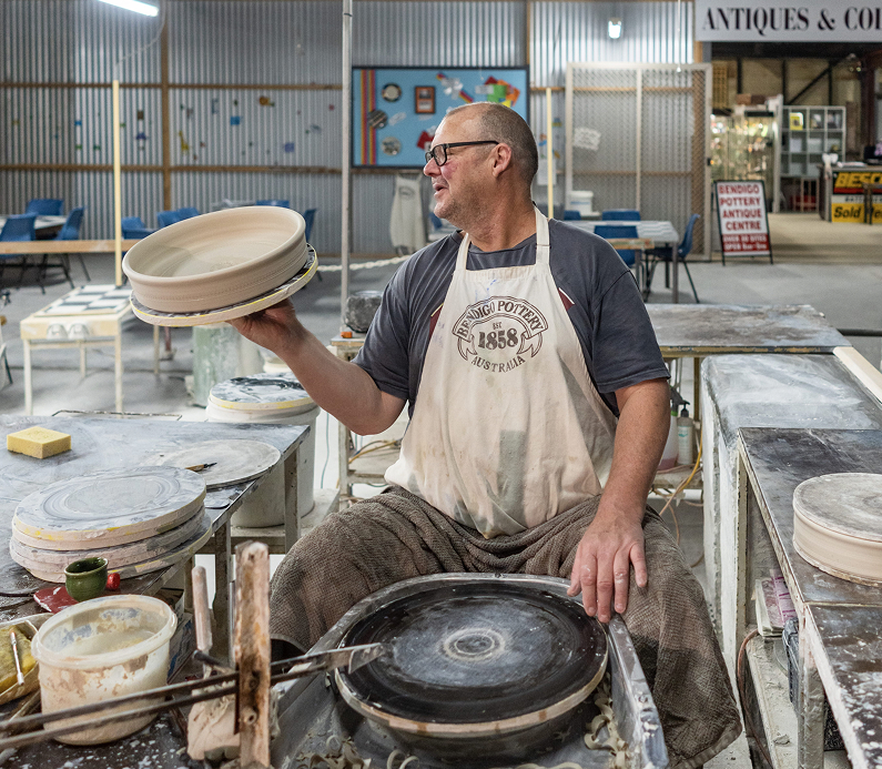 Person shaping clay into tableware on a potting wheel.