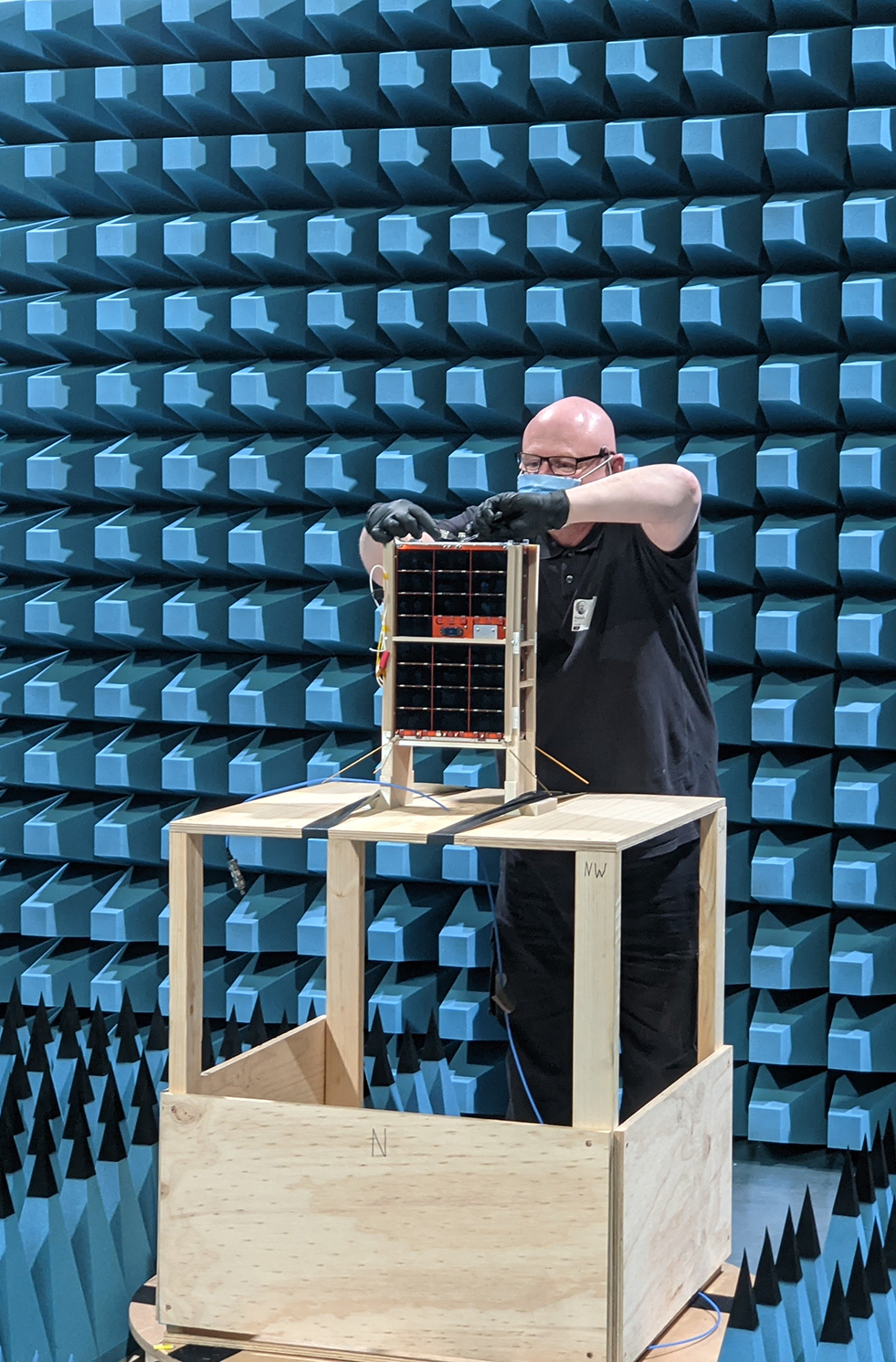 Darin Roberts connects a radio frequency cable to a spacecraft model during anechoic chamber testing at REDARC.