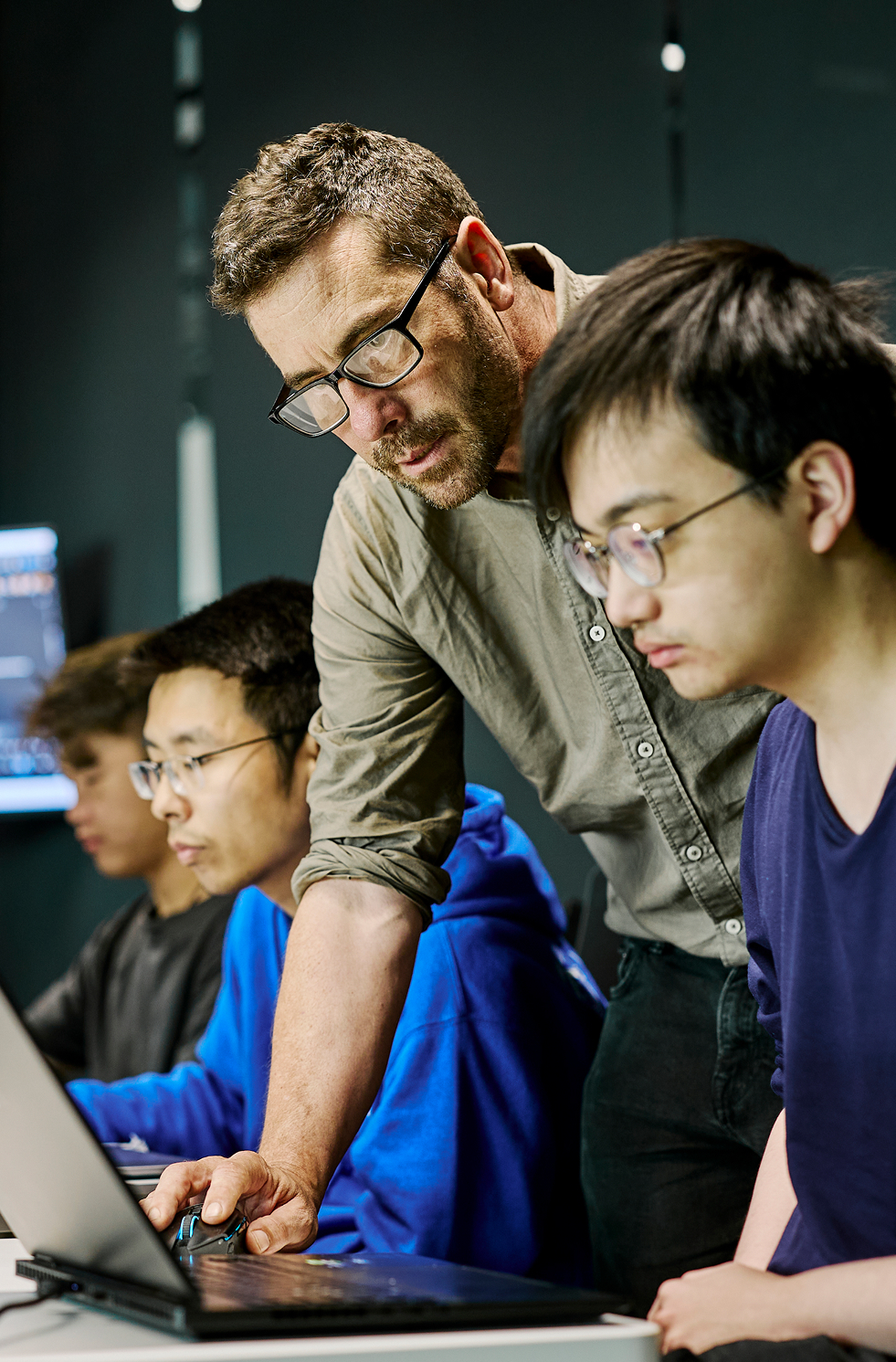 Diverse group of developer students and a teacher collaborating on laptops.