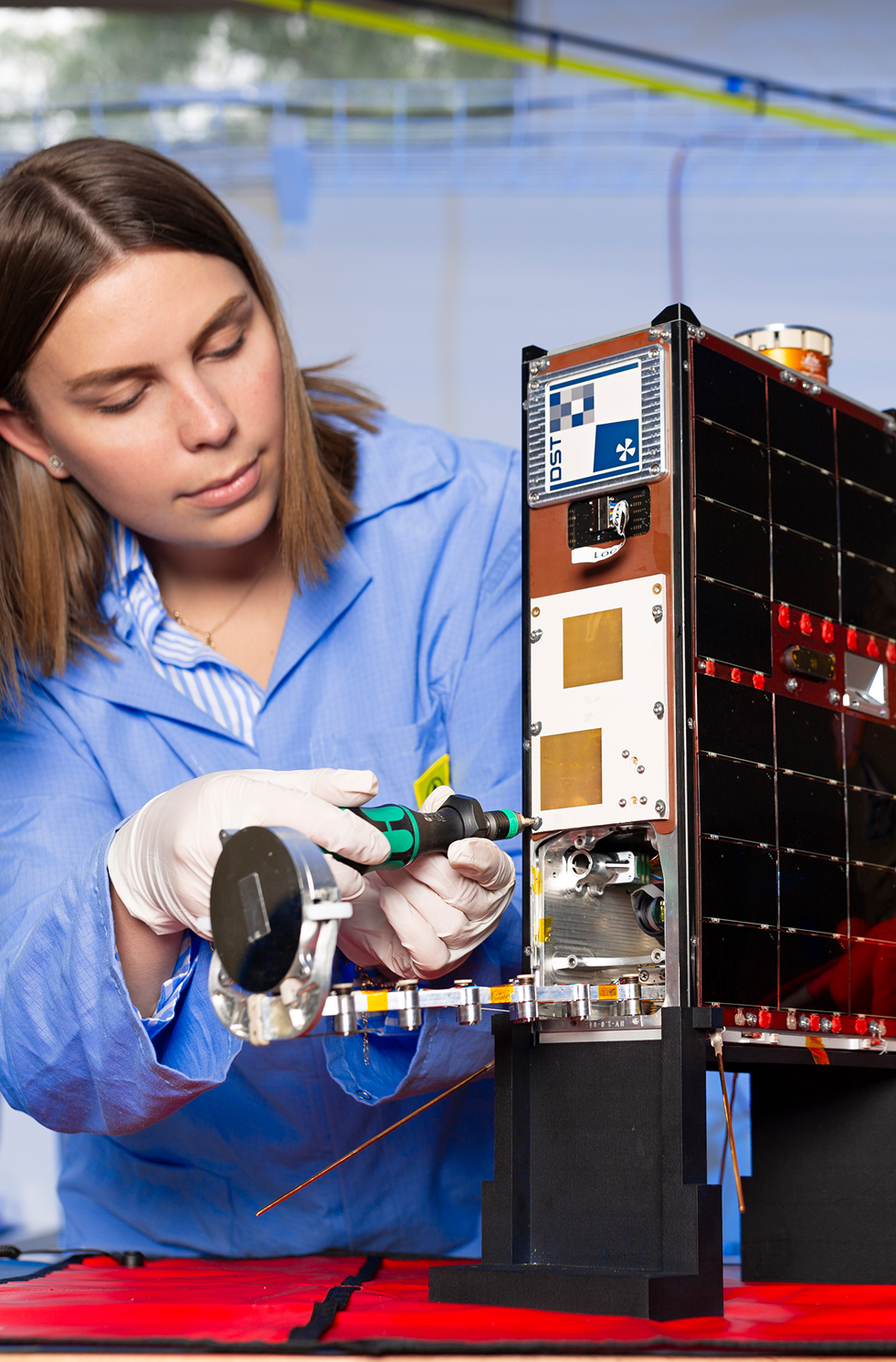 Franke Agenbag adjusting the Buccaneer CubeSat satellite in a laboratory.