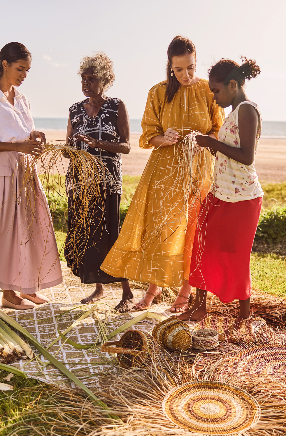 Group learning indigenous weaving techniques at Casuarina Coastal Reserve, Darwin, at sunset.
