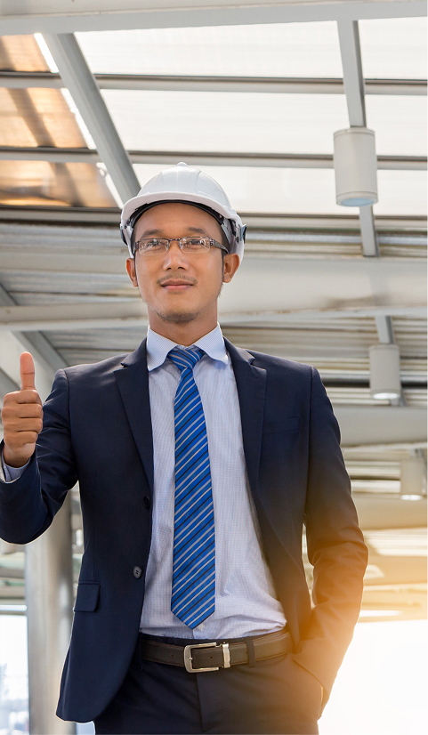 Construction manager in a suit and hard hat giving a thumbs up at an outdoor job site