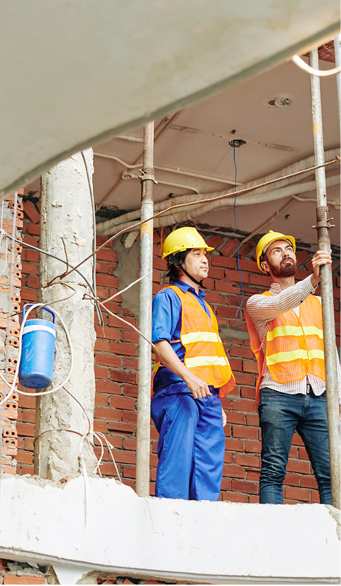 Construction workers in safety vests and helmets standing on scaffolding at a building site