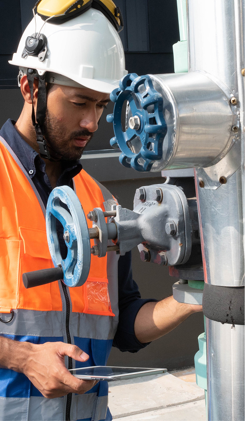 Engineer in a hard hat and reflective vest operating an overhead lifting control
