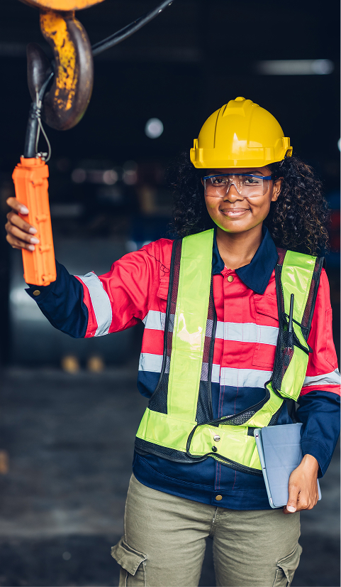 Factory technician in a hard hat and reflective vest operating an overhead lifting control