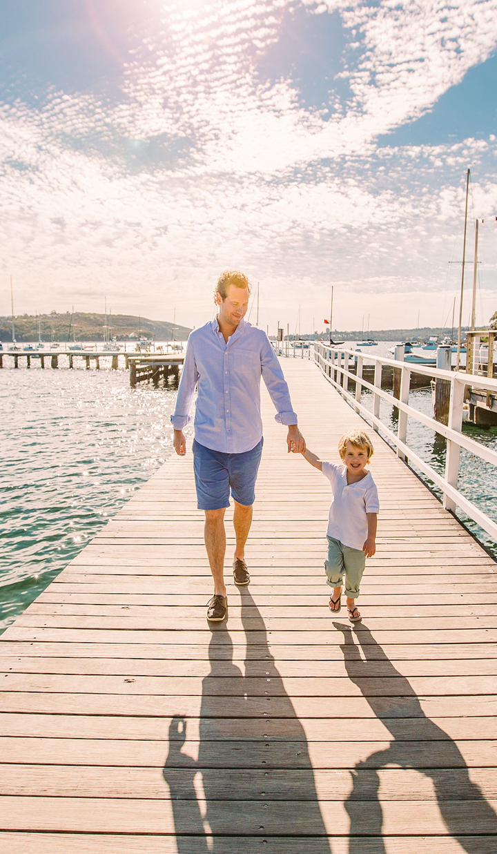 Father and young son walking hand-in-hand on a wooden pier
