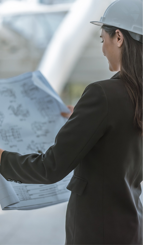 Female engineer in a hard hat reviewing architectural blueprints at a construction site