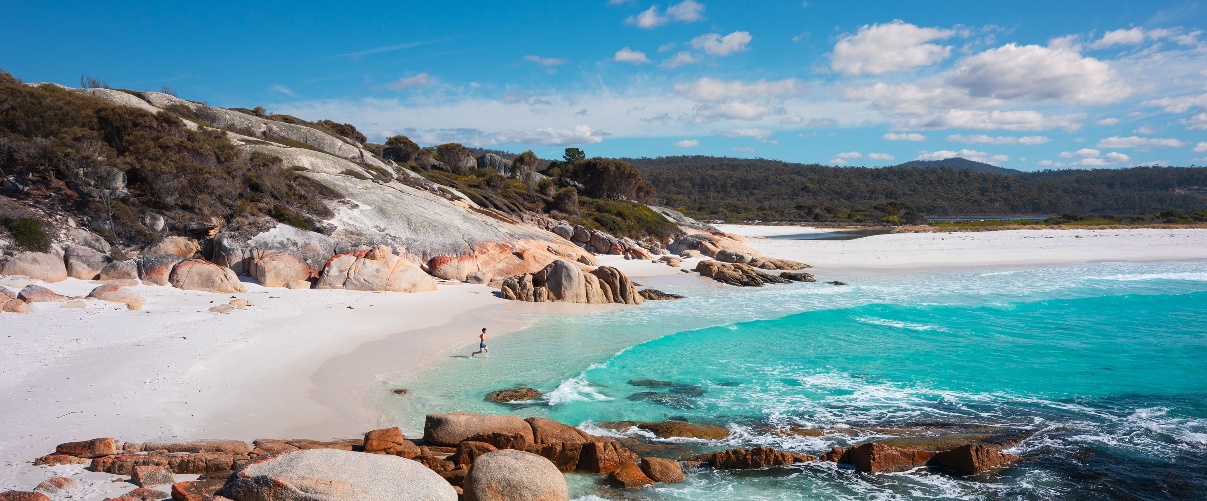 Person walking into the crystal clear waters of Sloop Reef on a sunny day