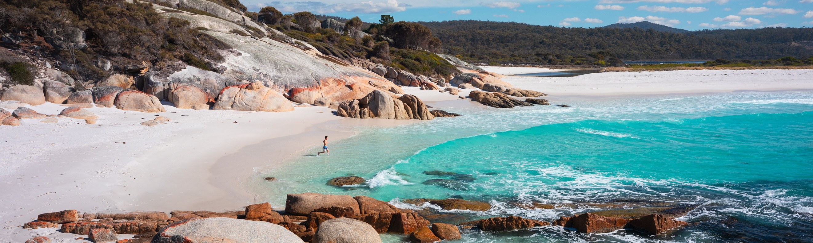 Person walking into the crystal clear waters of Sloop Reef on a sunny day