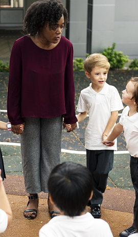 Pre-school teacher in playground with children