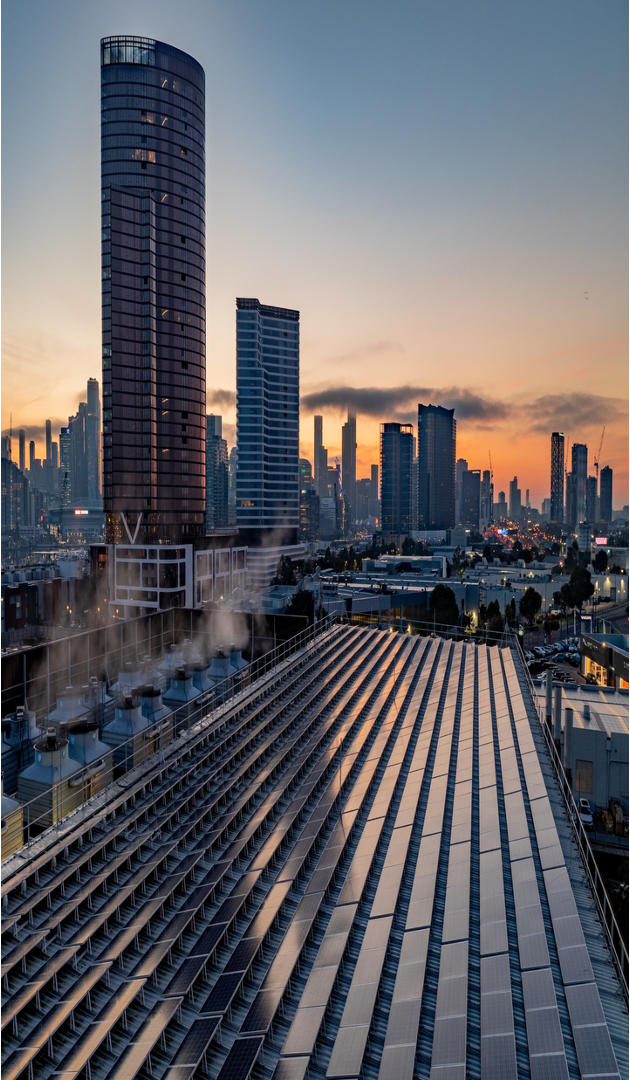 Melbourne city skyline at sunrise with solar panels in the foreground and high-rise buildings in the distance