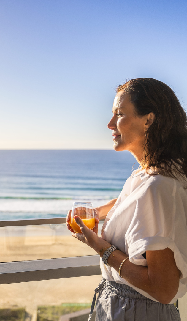 Woman standing on a balcony overlooking the ocean at sunrise