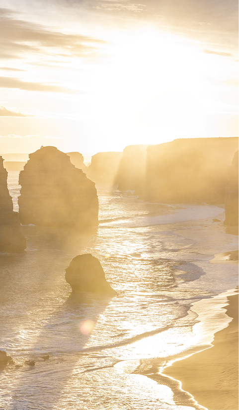 Sunset over the Twelve Apostles on the Great Ocean Road with golden light reflecting across the water and limestone cliffs
