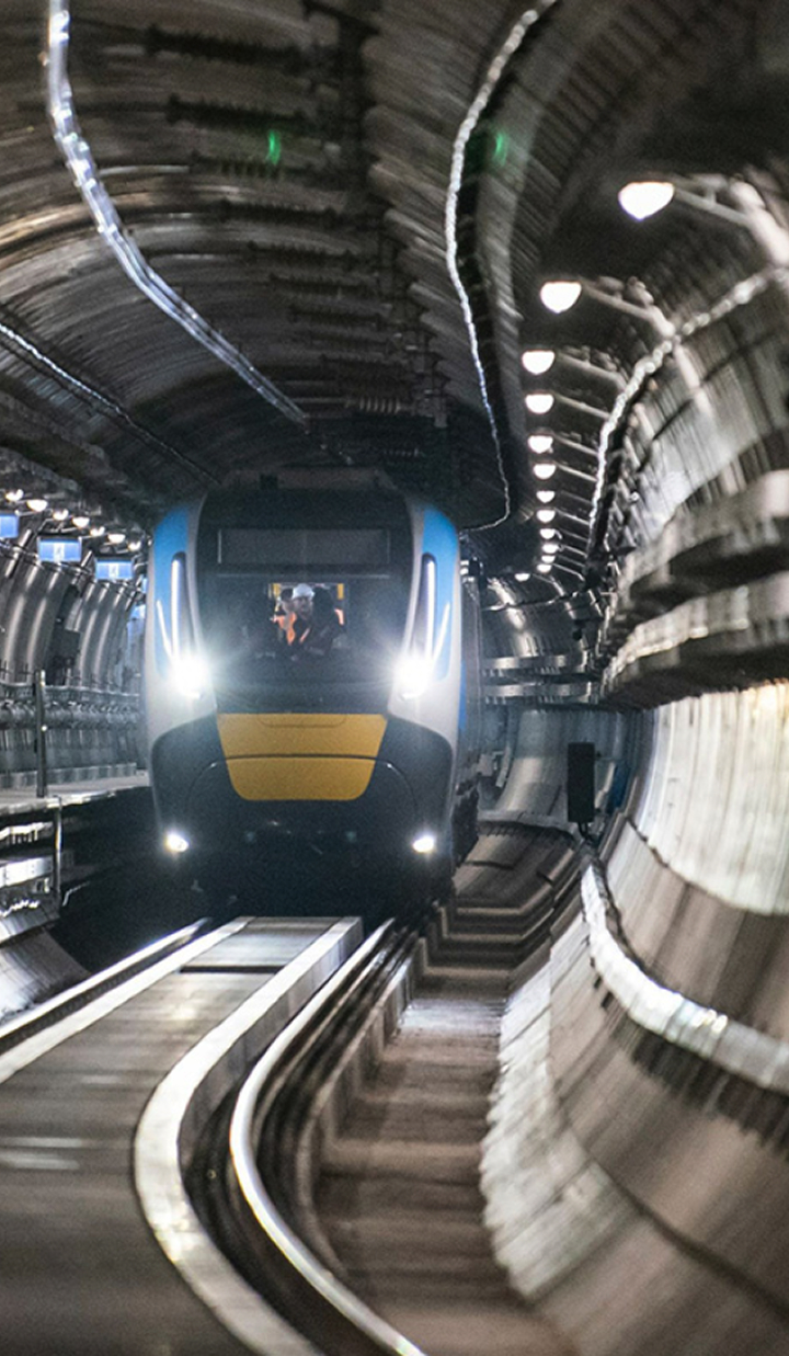 Metro Train running inside a tunnel with lights on shining along the rails.
