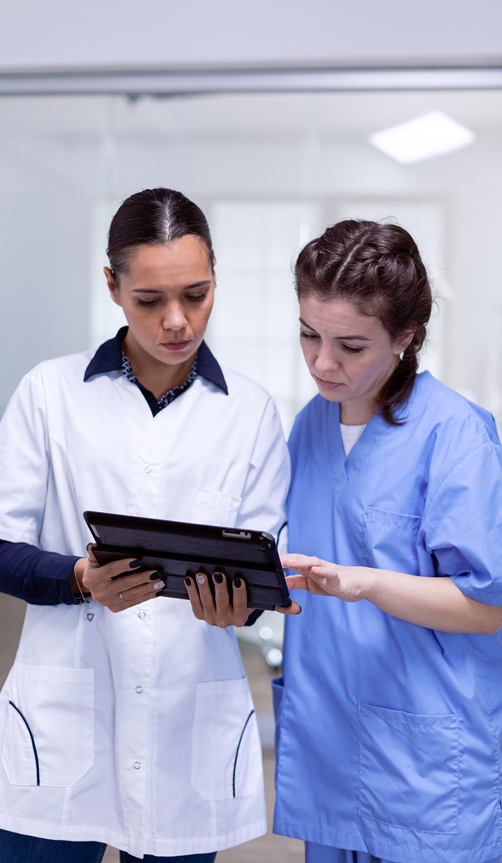 Two female medical professionals reviewing a digital tablet