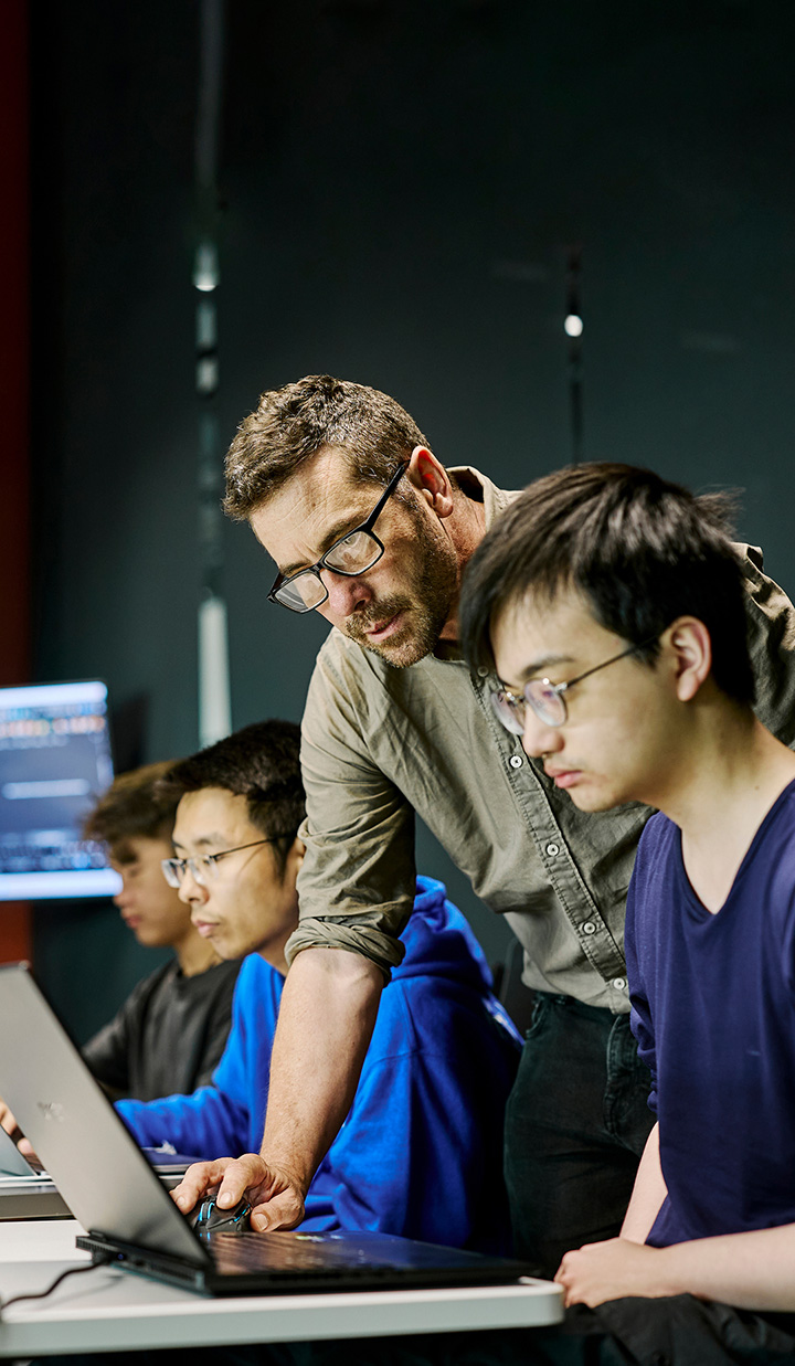 A Monash lecturer helping a student in front of a computer.