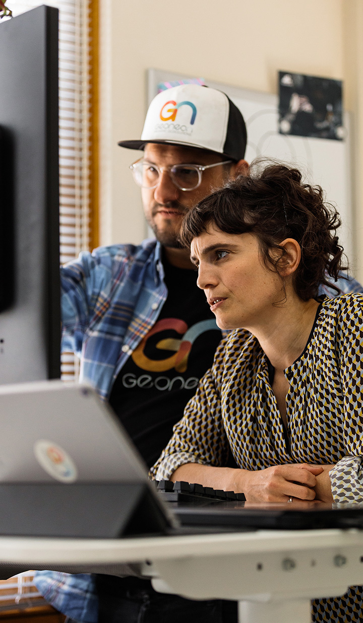 A man and woman working on a project together, looking at a monitor