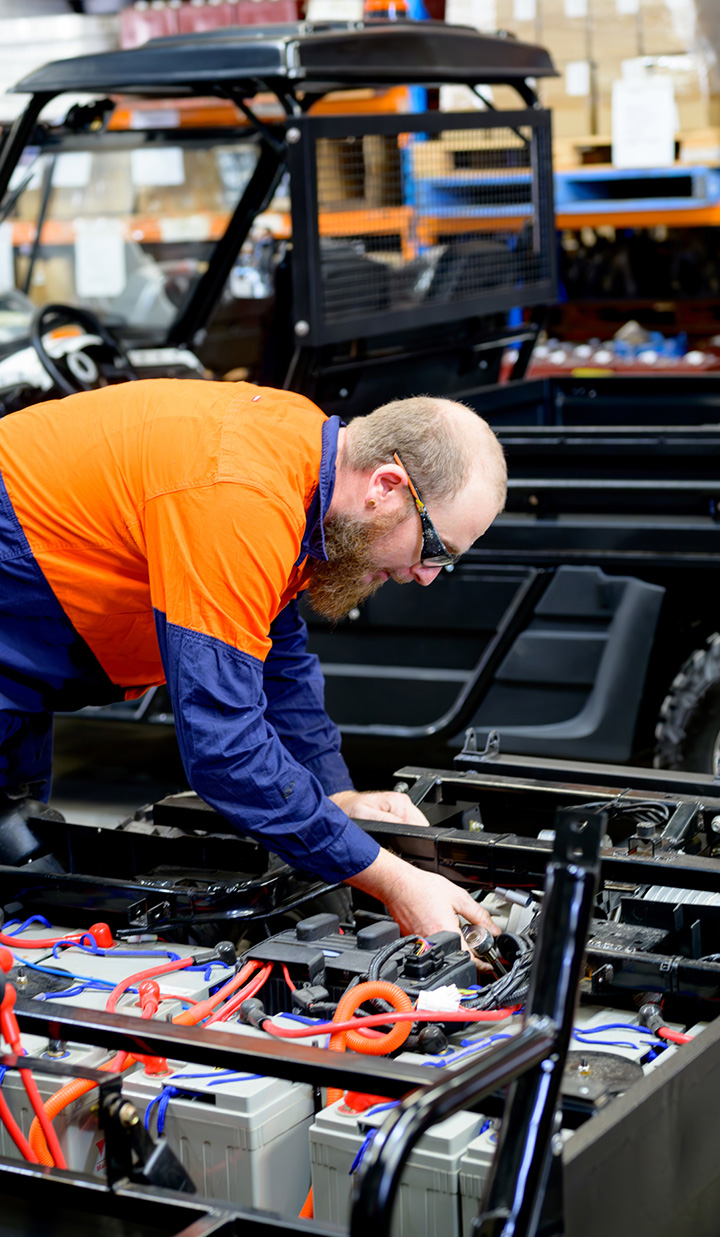 A man bent over a workstation working on car batteries