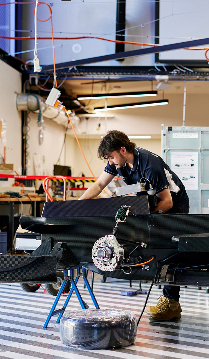 A man working on a vehicle chassis in a workshop with tools and equipment.