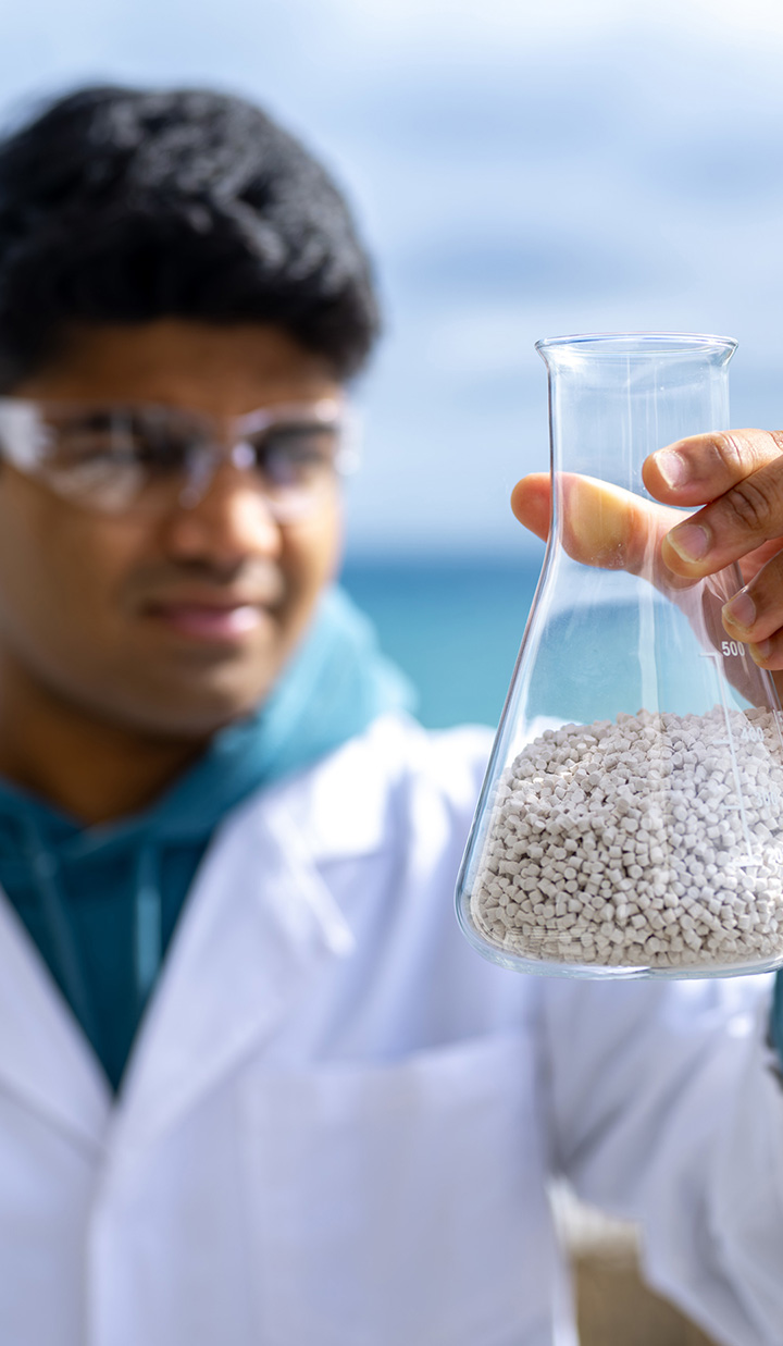 A person holding scientific glassware while wearing safety glasses