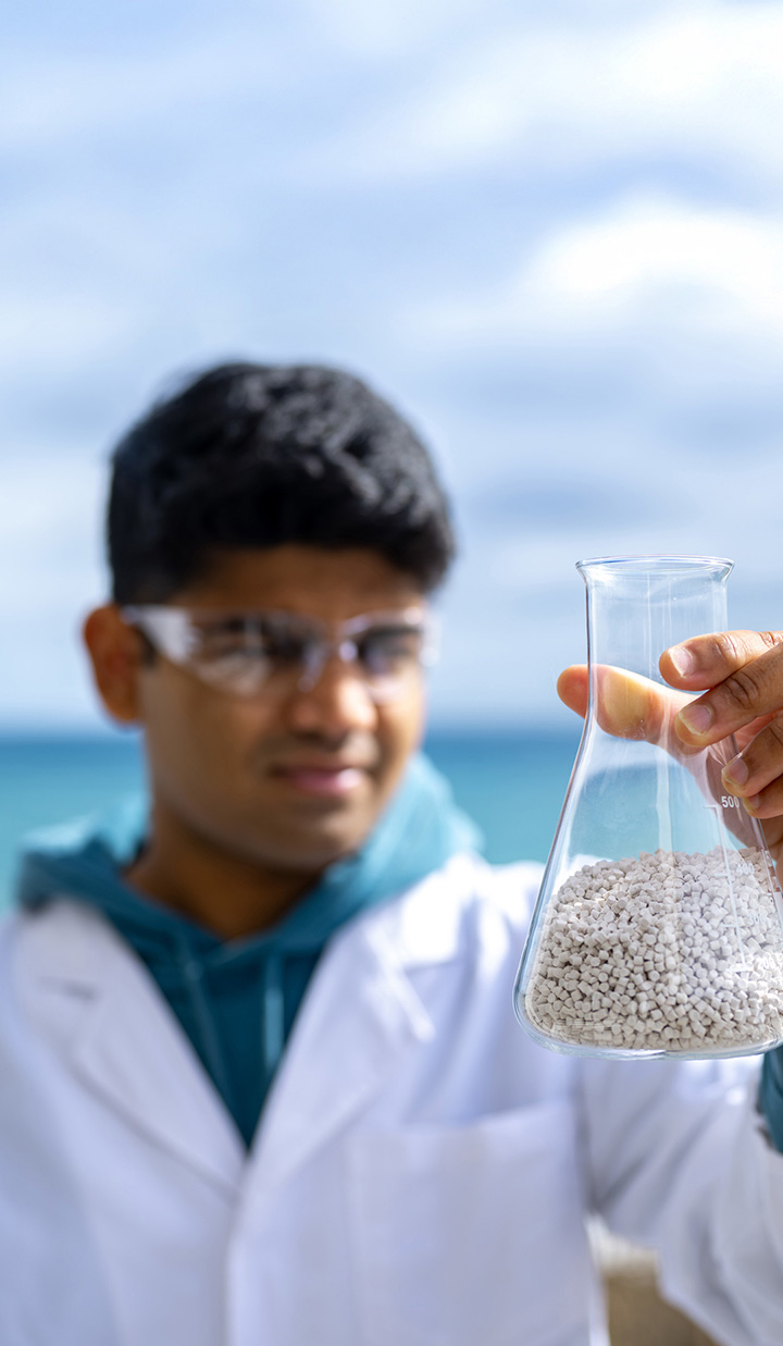 A person holding scientific glassware while wearing safety glasses