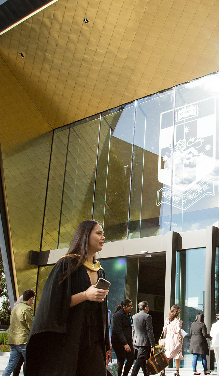 A student in front of UNSW wearing her graduation vest