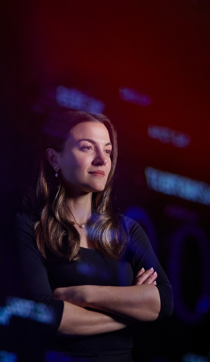 Ann Kayis-Kumar standing with arms crossed, looking confident.