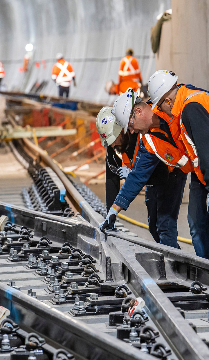 Construction workers inside a tunnel inspecting the rails of a metro system.