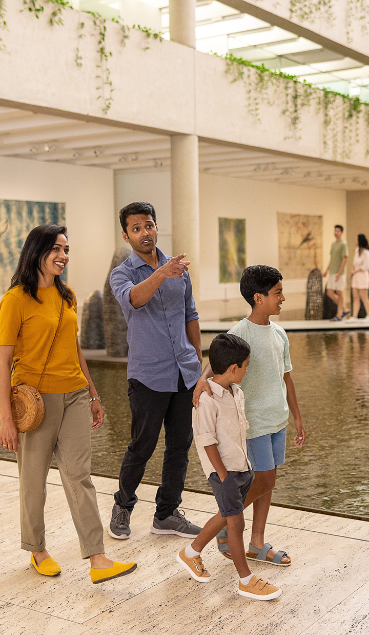 Family strolling through light-filled galleries at QAGOMA, admiring sculptures and paintings.