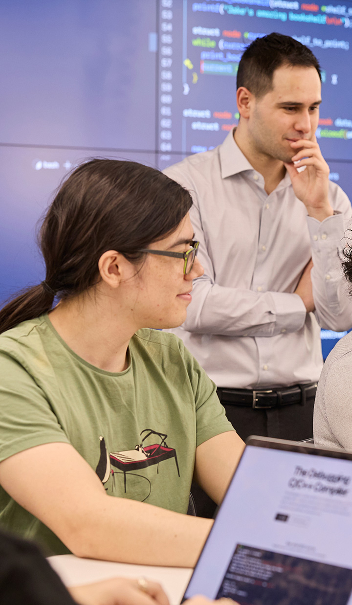 Students from UNSW coding in class while a lecturer observes.