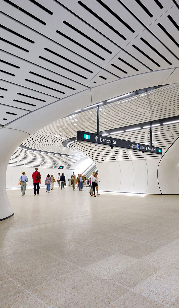 Train station exit to Denison St and directions to the bus station at Miller St, with commuters accessing the escalator