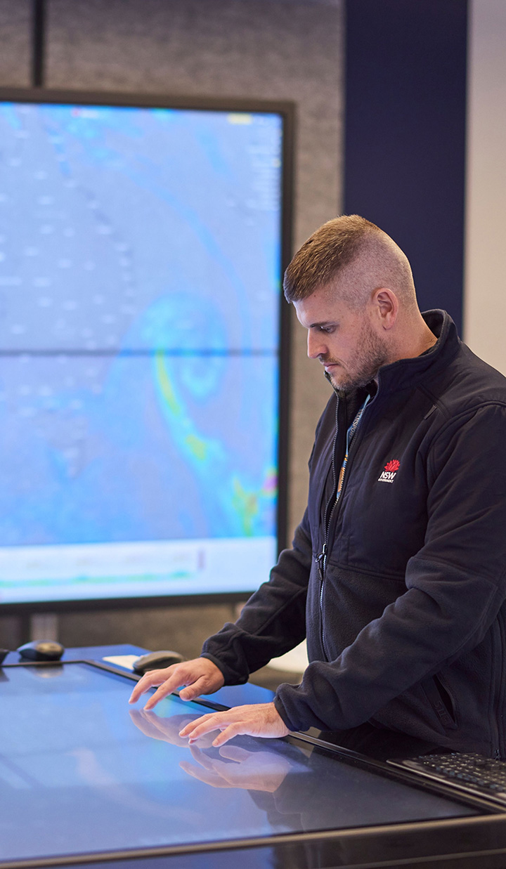 Transport NSW employee interacting with touchscreen table monitoring the weather and the system.