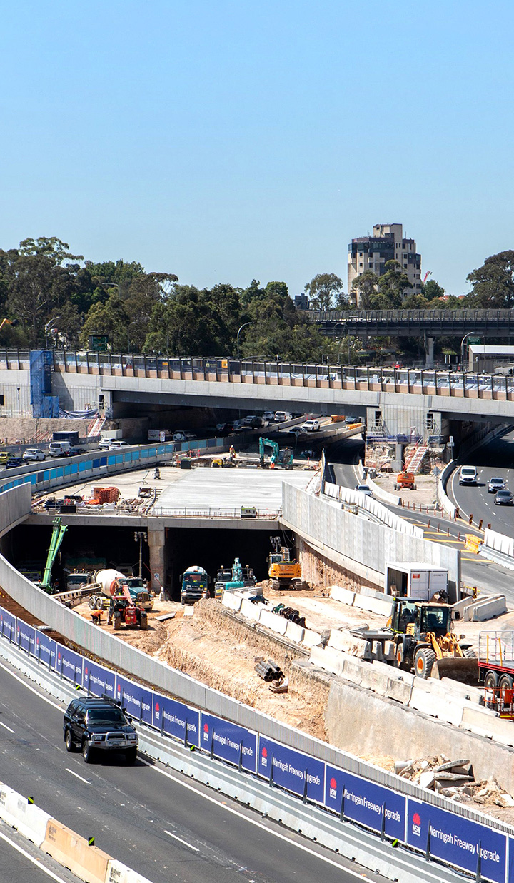 Warringah Freeway upgrade under construction, with walls and machines parked under a flyover pass.